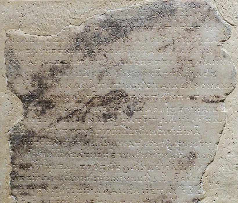 Fragment kamiennej płyty z rzędami greckich liter; nad tekstem drobne znaki zapisu muzyki